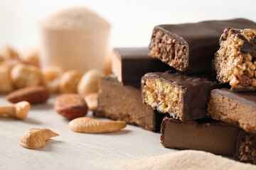 Different tasty protein bars and nuts on white table, closeup. Space for text