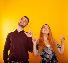 a girl with red hair and a brunette guy point up with their index fingers in place for the text....