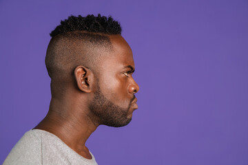 Side view. African-american young man's portrait on purple color studio background. Concept of human emotions, facial expression, youth, feelings, ad.