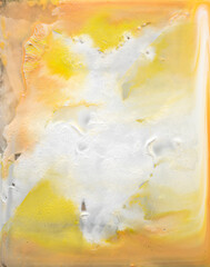 Abstract yellow and peach paint on glass surface.