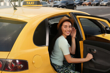 Beautiful young woman getting out of taxi on city street