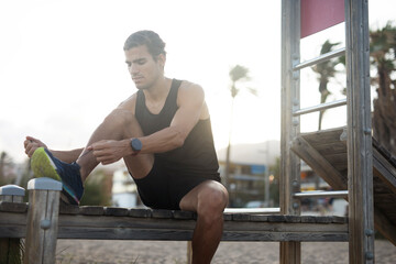 Sporty athletic man exercises at the beach. Handsome man training outdoors.