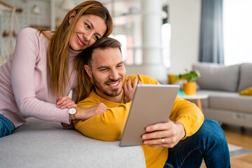 Happy couple spending time with tablet at home