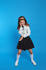 Back to school and happy time. Funny schoolgirl playing and act like dj over blue paper wall...