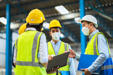 The factory employee consists of engineers, foreman, technicians, and related department staff. Wear a mask, hard hat, and vest. meeting before starting work inside the warehouse. Teamwork concept.