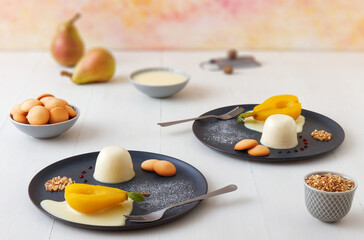 Panna cotta, traditional Italian dessert with muscat poached pears and creme Anglaise, crushed...