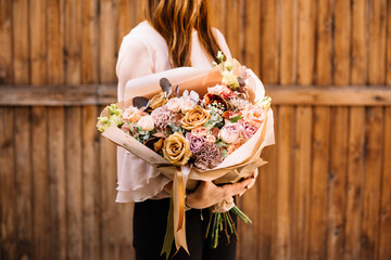 Very nice young woman holding big and beautiful bouquet of fresh eustoma, roses, cymbidium,...