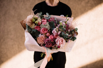 Very nice young woman holding big and beautiful bouquet of fresh roses, carnations, eucalyptus,...