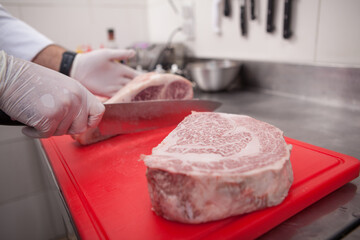 Close up of a marbled beef raw meat on cutting board, chef working on background