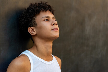 Afro latin male teenager against a wall, looking up.