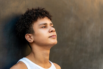 Afro latin male teenager against a wall, looking up.