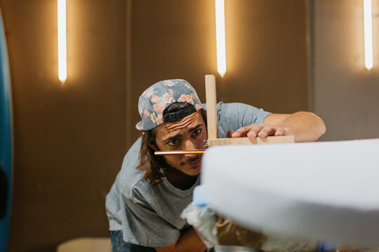Focused male surfboard shaper suing scribe tool