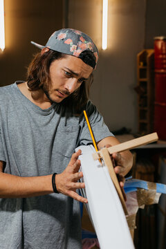 Focused male surfboard shaper suing scribe tool