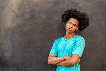 Portrait of young afro latin man against a black wall