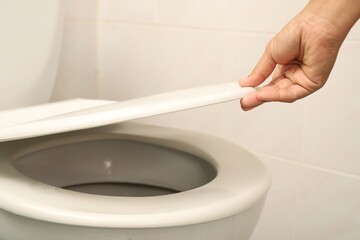 Woman using hand to open toilet lid