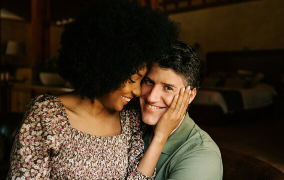 Tender multiracial couple hugging in house