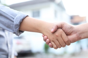 Men and women shake hands to agree to buy and sell houses.