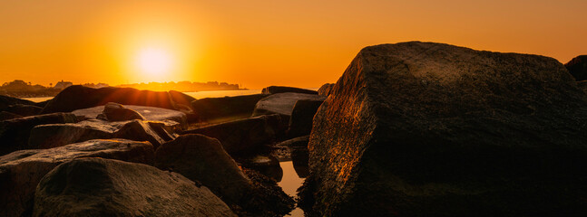 Rising sun over the rocky cliff in the ocean