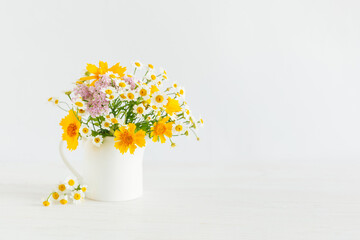 Beautiful summer flowers in a jar on a white background.