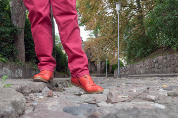 Legs in red on cobblestone street.