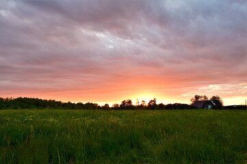 Beautiful multicolored sky over the roofs of houses in the village. Summer sunset. Copy space