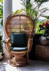 Peacock wicker rattan chair and flowers in living room overlooking the garden. Wicker chair interior decor. No focus, specifically.