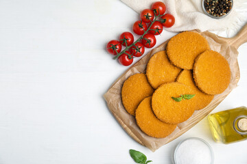 Fototapeta na wymiar Delicious fried breaded cutlets served on white table, flat lay. Space for text