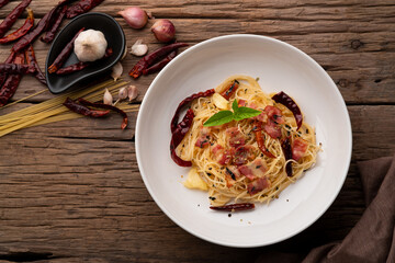 Stir-Fried Capellini pasta With Dried Chili And Crispy Bacon on white plate.Top view