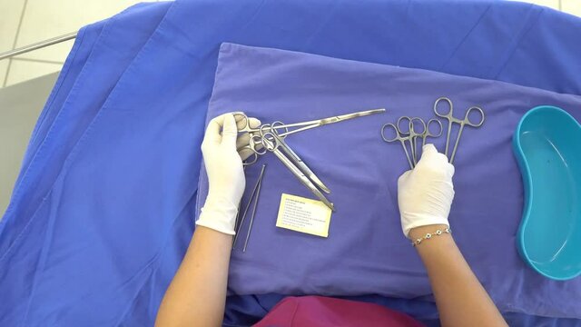 nurse hands with latex gloves preparing surgical equipment to be used in operating room