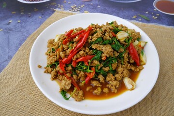 Stir fried basil with minced pork on white dish on sackcloth on black background.street food 