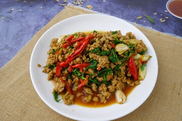 Stir fried basil with minced pork on white dish on sackcloth on black background.street food 
