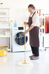 Asian senior elderly woman housewife holding mop with plastic bucket, clean up floor mobbing in...
