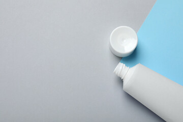 Blank tube of toothpaste and lid on color background, flat lay. Space for text