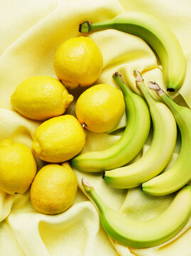 Overhead View Of Bananas And Lemons On Yellow Cloth