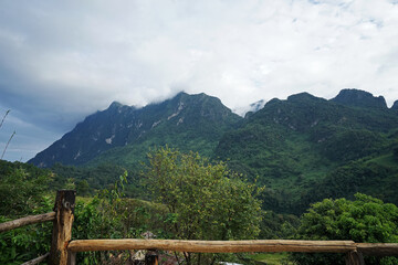 Fototapeta premium View of high green mountain and cloudy blue sky from wooden balcony