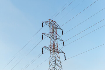 High-voltage power lines electricity transmission pylon on blue sky background.