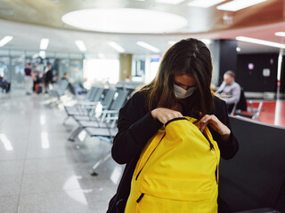 a woman sits at the airport and looks into a yellow backpack passenger