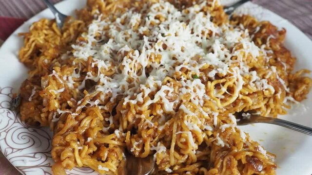 Cheese Maggie Noodles, Instant Noodles served in plate topped with cheese and then placed over a colored background, selective focus.Cheese and garlic Maggie view in the white plate.