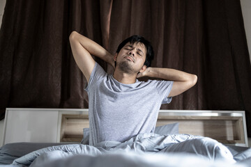 Asian man stretching in the morning at bedroom after waking up