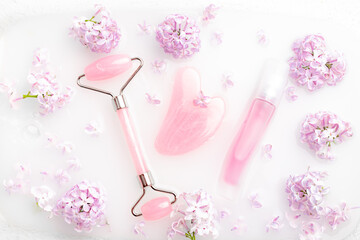Roller facial massager and lilac in milk . Facial care. Skin care. Cosmetology. Massage. Lilac bush.