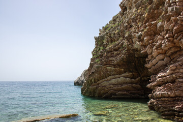 Naklejka premium Rocky seaside coast. Boulders are standing in the beautiful water. Group of large stones against the blue sky. Big stone on the background of the sea.