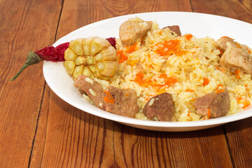 Cooked pilaf on white dish on the old rustic table