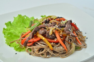 asian cooked udon dark noodles White plate with wok