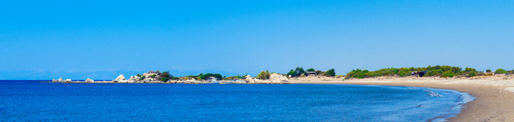 Obraz premium Panorama of bay coastline with dunes, small houses and boats. Sand dunes with green bushes and rocks. Panoramic view of sandy beach in the bay.