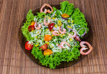 Vegetable salad with boiled shrimp tails on glass dish
