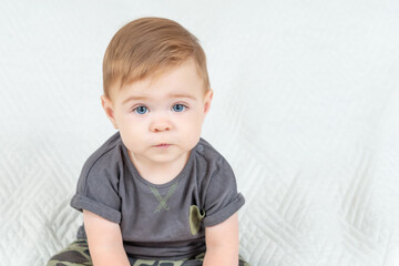 Naklejka premium Close-up portrait of a nine-month-old baby boy over white background. Adorable red haired kid looking at camera. Copy space.