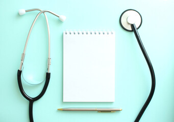 On a blue background, a stethoscope and a white notepad with blank space for inscription.