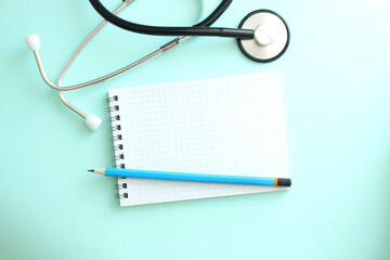 White notepad with blank space for inscription and a stethoscope on a blue background.