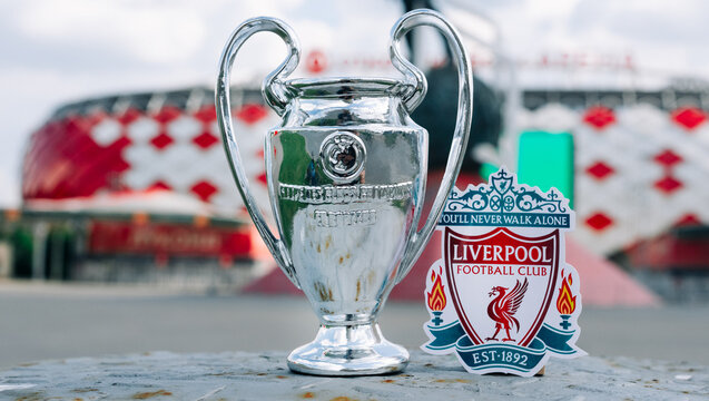 June 14, 2021 Liverpool, UK. Liverpool F.C. Football Club emblem and the UEFA Champions League Cup against the backdrop of a modern stadium.