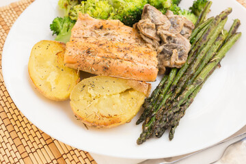 delicious dish of fried river trout fillet with garnish of broccoli, asparagus sprouts, baked potatoes and mushroom sauce